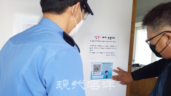 태안해경 관계자가 관내 해상낚시터 시설내에 ‘QR코드로 듣는 안전수칙 스티커’를 배포, 부착하고 있다.