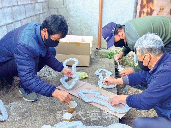 주민들이 폐 밧줄을 활용해 재난재해 안내판을 만들고 있다.
